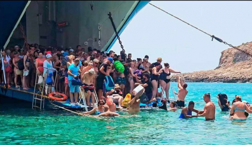 A Creta niente molo, turisti costretti a entrare in acqua con i bagagli sulla testa  per sbarcare o salire a bordo dei traghetti – Il video 